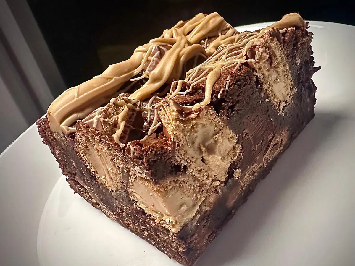 A slice of layered chocolate cake with cream filling on a white plate.