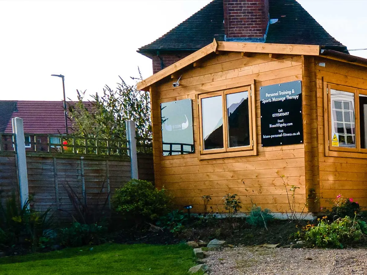 The front of Bison Personal Fitness, a timber-clad building with a black sign advertising personal training and sports massage therapy.