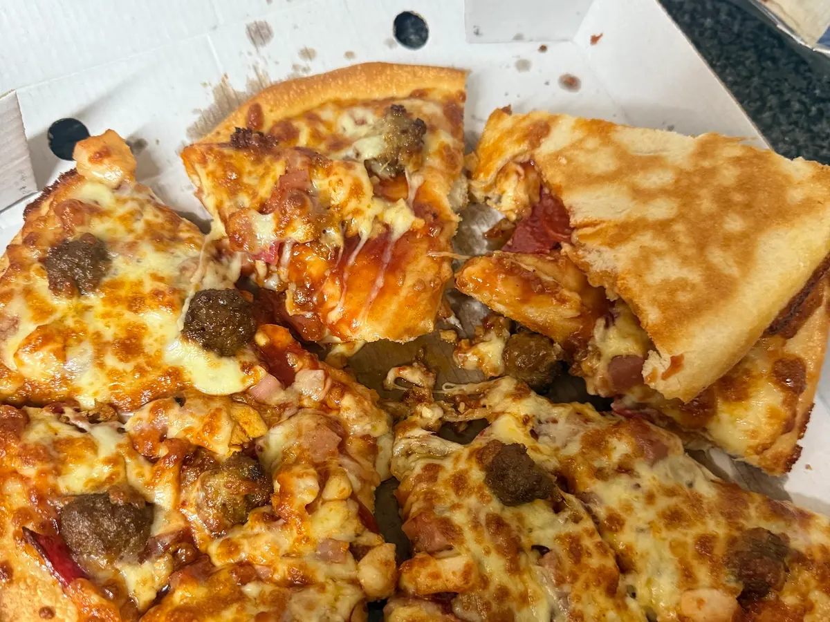 A pizza from Family Grill with pepperoni and various toppings on white paper in a cardboard box.