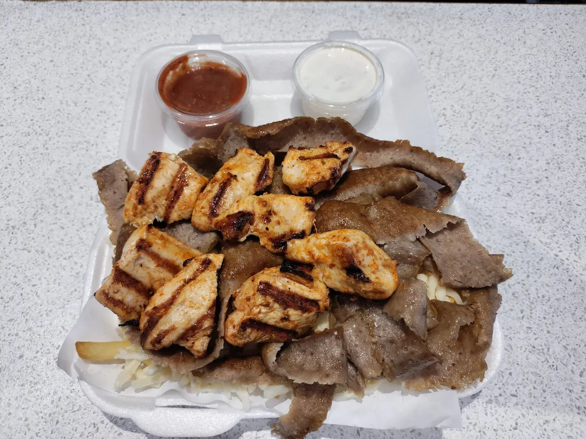 A meat and kebab platter from Family Grill with grilled chicken skewers and various sliced meats on a takeaway container.