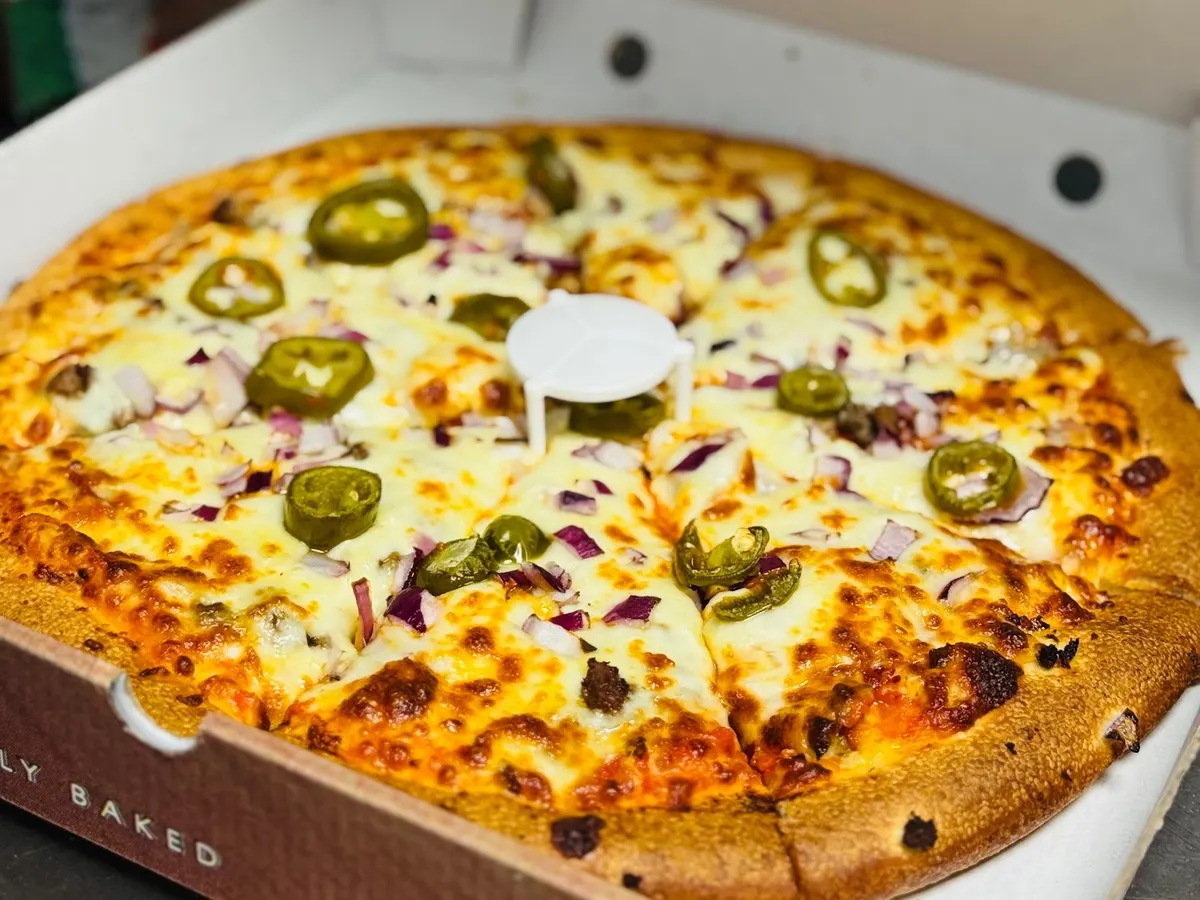 A spicy jalapeño pizza from Fat Sam's with green peppers, onions and toppings on a branded box.