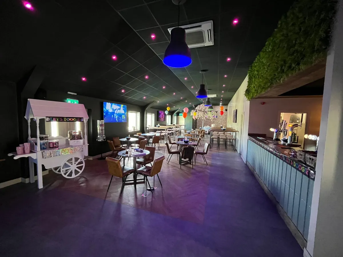 Inside Fox In The Box showing the venue with neon lighting, colorful decorations, popcorn machine and tables.