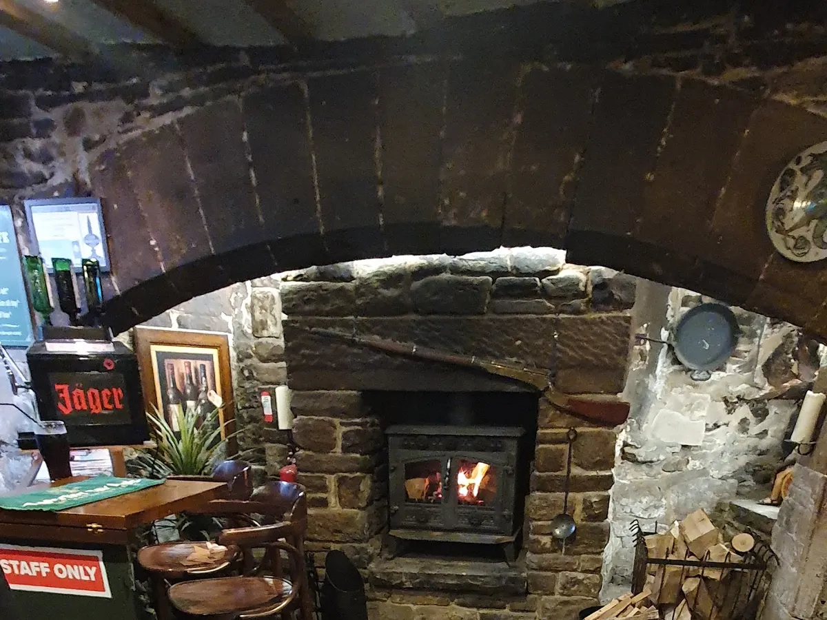 The interior of the Green Dragon showing a stone fireplace with a cast iron stove, bar counter, and pub furnishings.