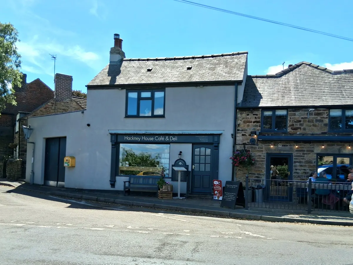 The storefront of Hackney House Café & Deli, a white-rendered building with blue-framed door and windows, showing the cafe name on the sign.