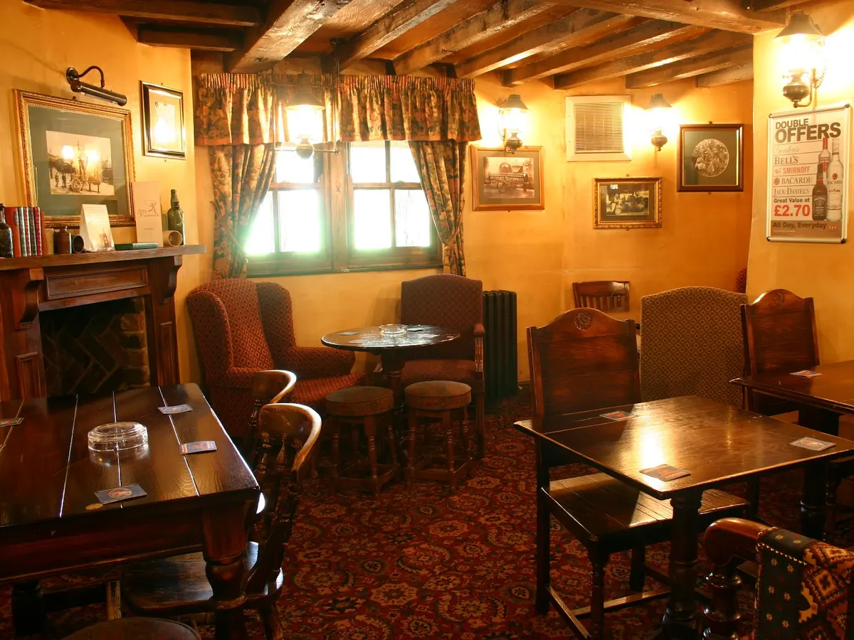The warm interior of the Jolly Farmer showing an inviting lounge area with wooden beams, fireplace, and period furnishings.
