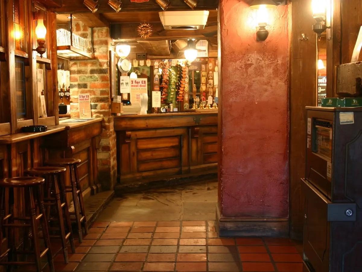 Inside the Jolly Farmer pub showing the wooden bar, bar stools, warm lighting, and traditional pub interior.