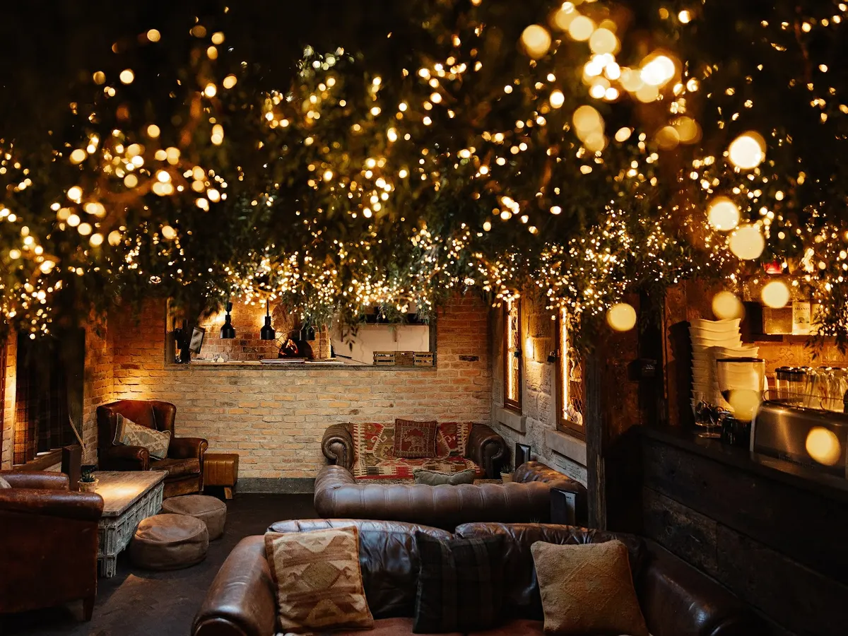 Inside seating area with leather chairs and sofa under decorative lights.