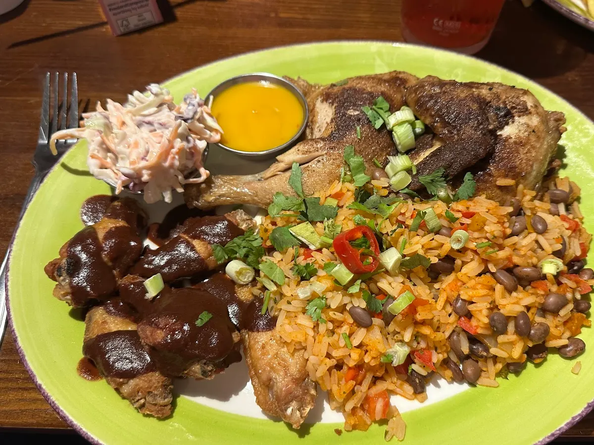 A plated meal with grilled meat, cooked vegetables, rice, and sauce.