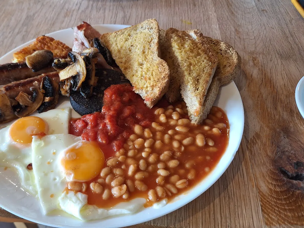 A breakfast plate with eggs, bacon, sausage, beans, toast, and mushroom.