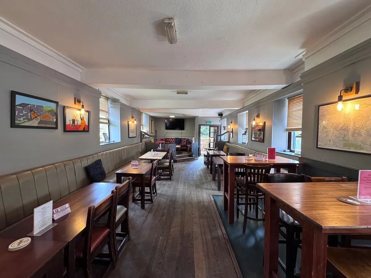 The seating area inside The Dronfield Arms pub with booth seating, wooden tables, and interior lighting.