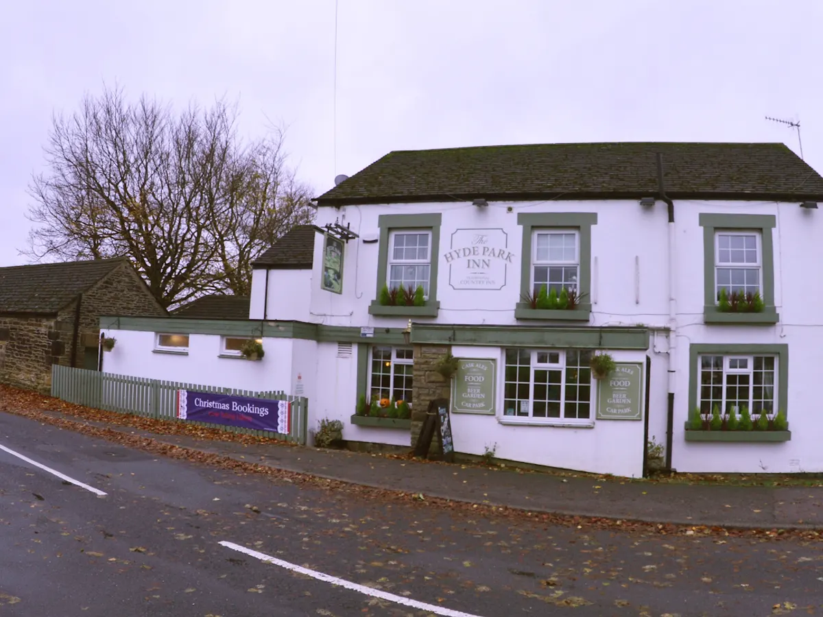 The white and stone building exterior of The Hyde Park Inn with the name sign visible and a Christmas Bookings banner.