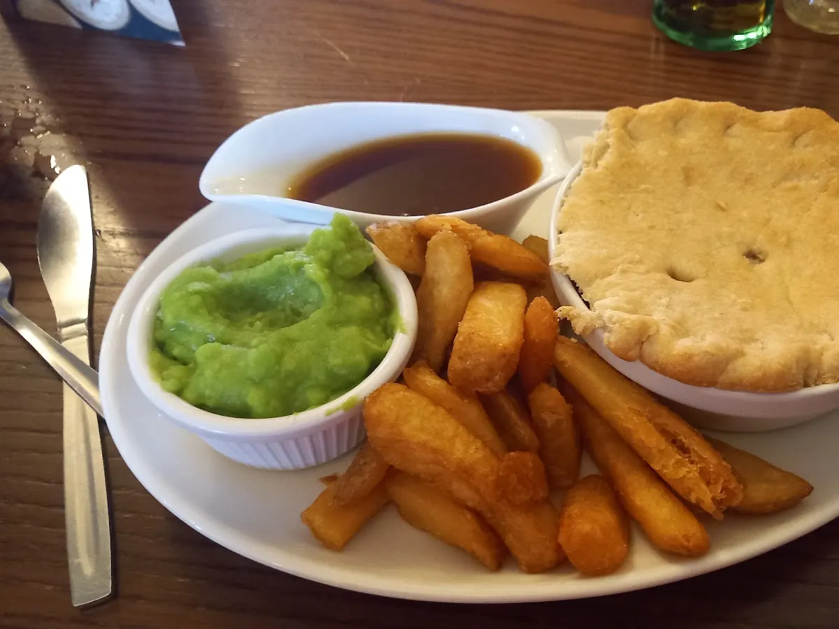 A plate of fish and chips with mushy peas and gravy, typical food served at The Hyde Park Inn.