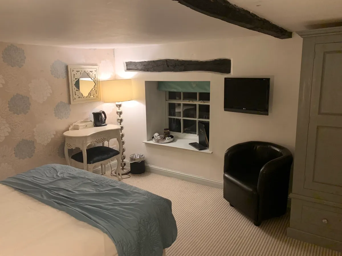 A hotel bedroom in The Manor House Hotel & Restaurant with a double bed, dressing table, armchair, and en-suite bathroom.