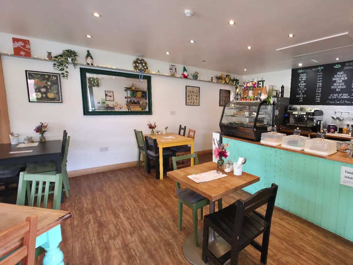 The interior of The Snug café showing seating areas with colourful chairs, counter, decorations on walls, and menu board visible.