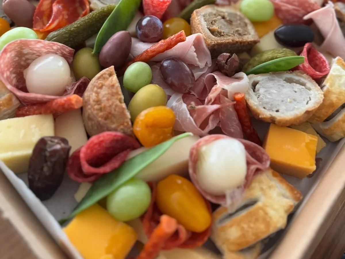 An artfully arranged charcuterie board with cured meats, cheeses, olives, and bread.
