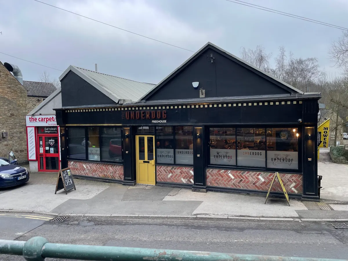 The Underdog Freehouse exterior showing black building with yellow door, brick pattern detail, and storefront signage.
